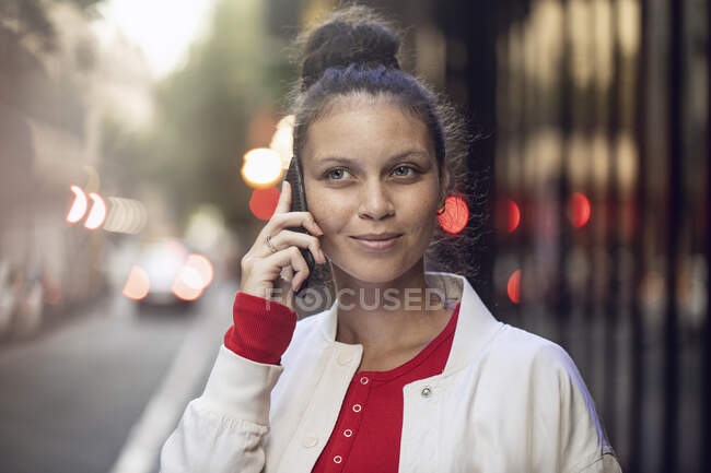 Retrato de una joven al teléfono en la ciudad - foto de stock