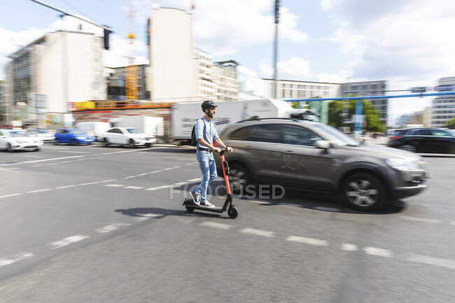 Businessman riding e-scooter on the street in the city, Berlin, Germany — Stock Photo