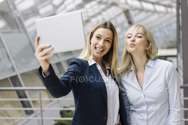 Zwei glückliche junge Geschäftsfrauen mit Tablet im Büro — Stockfoto
