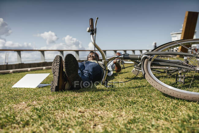 Joven con bicicleta, relajante, tumbado en la hierba - foto de stock