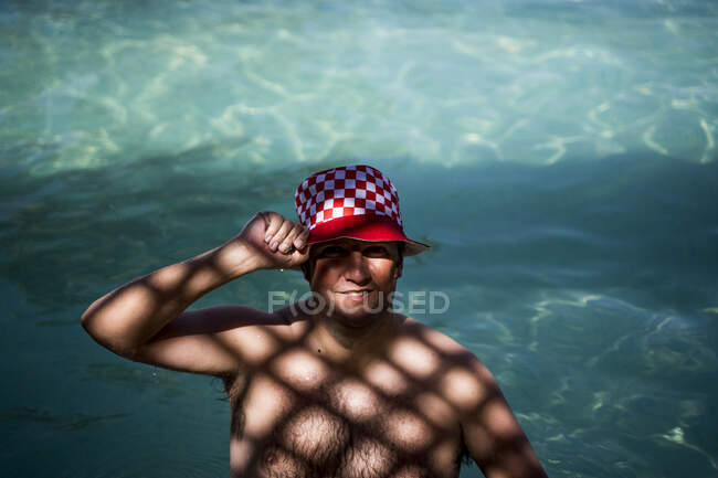 Portrait of overweight man with hat in pool in shady area — Stock Photo