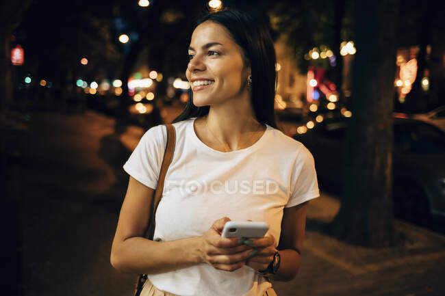 Молода жінка вночі користується смартфоном у місті. — стокове фото