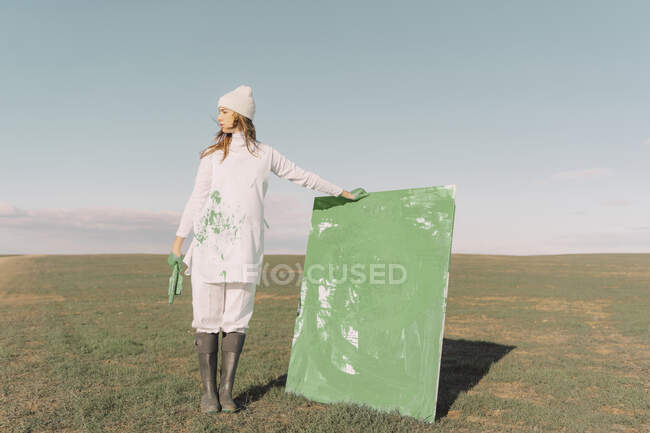 Giovane donna in possesso di pittura verde su campo asciutto — Foto stock