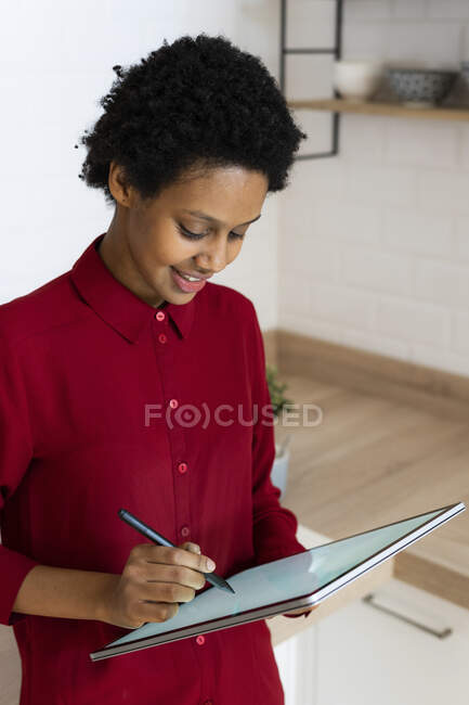 Giovane donna che utilizza tablet grafica a casa — Foto stock