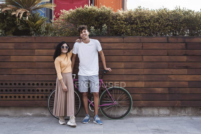 Glückliches Paar mit Fahrrad steht an der Wand — Stockfoto