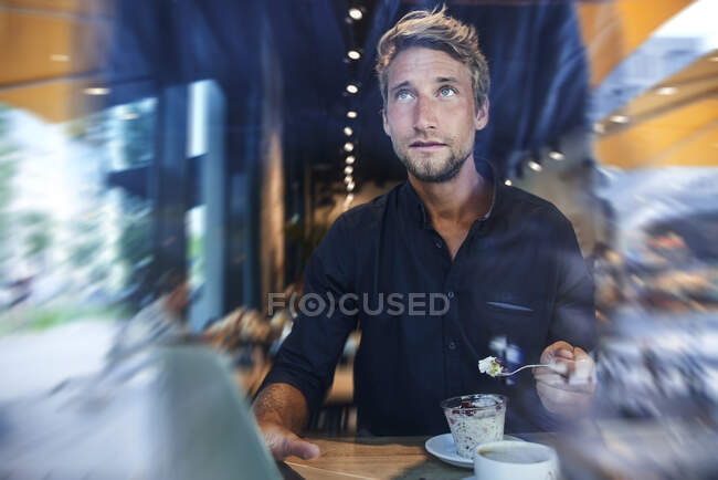 Young businessman in a cafe eating muesli — Stock Photo