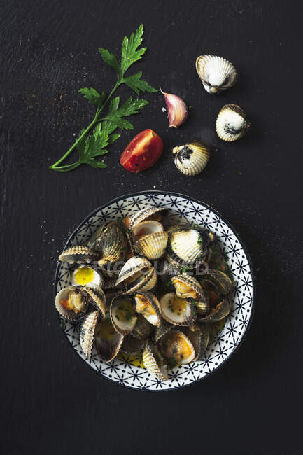 Directly above shot of clams in plate by ingredients on black background — Stock Photo