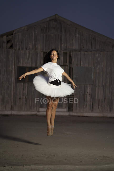 Ballerina che balla davanti a una capanna di legno la sera — Foto stock