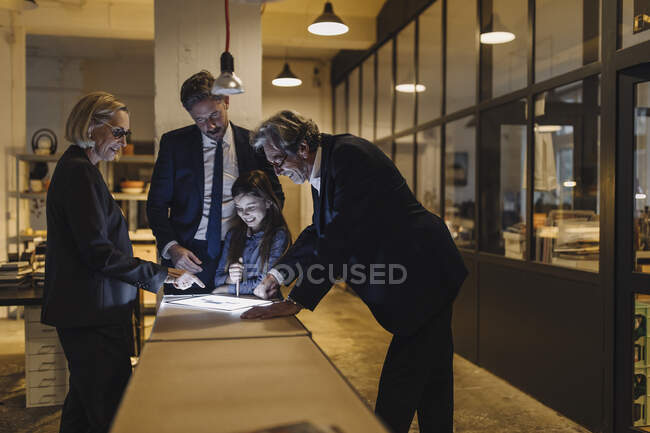 Gente de negocios y chica mirando tableta brillante en la oficina - foto de stock