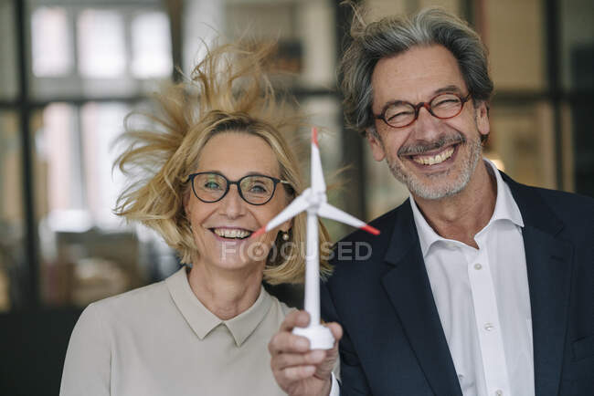 Portrait d'un homme d'affaires heureux et d'une femme d'affaires tenant un modèle d'éolienne en fonction — Photo de stock