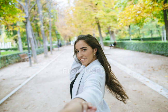 Portrait de femme souriante dans le parc marchant main dans la main — Photo de stock