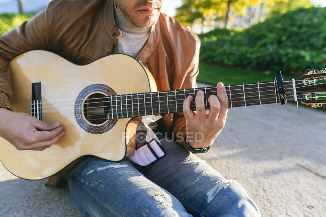 Primo piano di un uomo che suona la chitarra in un parco — Foto stock