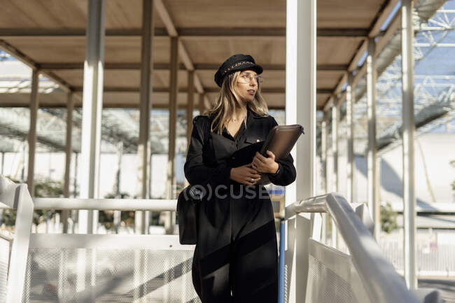 Молодая блондинка в черной матросской кепке с сумкой для ноутбука — В движении, Счастливый - Stock Photo