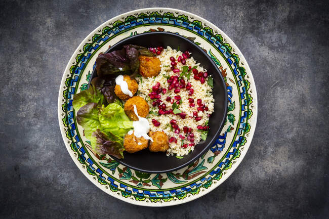 Bowl of falafel with lettuce, yogurt, pomegranate seeds, parsley, mint and Tabbouleh salad — Stock Photo