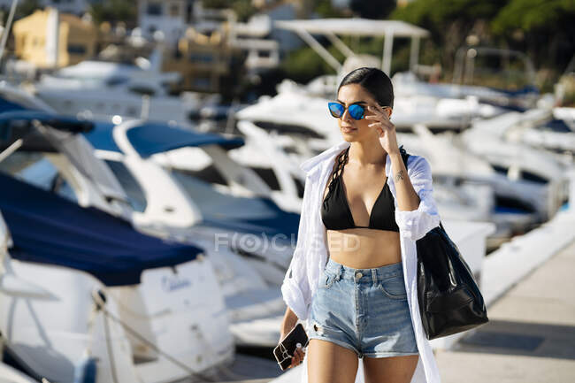 Jeune femme avec un sac marchant dans une marina — Photo de stock