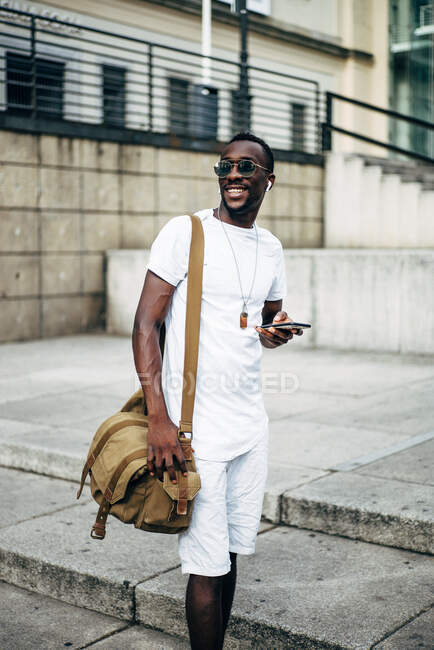 Junger Mann mit Kopfhörer und Handy in der Stadt — Stockfoto