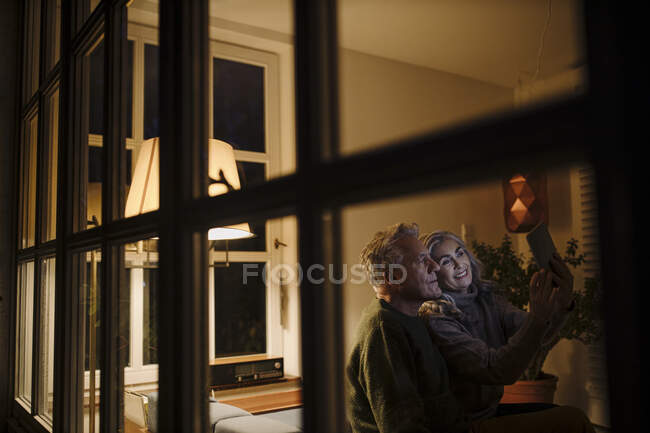 Seniorenpaar nutzt Tablet nachts zu Hause — Stockfoto
