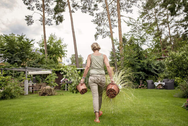 Задній вид на жінку, що ходить у саду з рослинами. — стокове фото