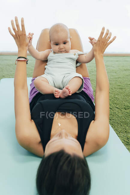 Молода мама і дитина займаються фізичними вправами на йога маті. — стокове фото