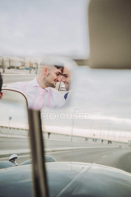 Reflet dans le rétroviseur d'un élégant couple gay dans une voiture décapotable vintage — Photo de stock