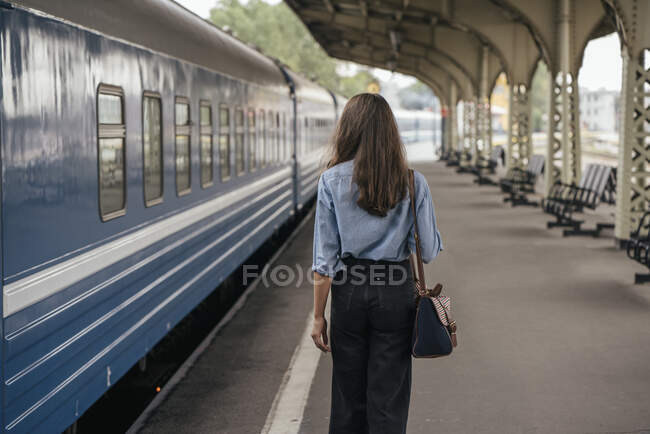 Rückansicht einer jungen Reisenden auf dem Bahnsteig — Stockfoto