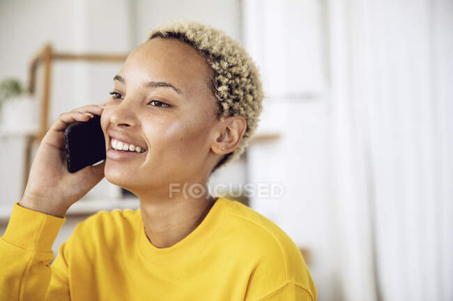 Portrait of happy young woman on the phone at home — Stock Photo