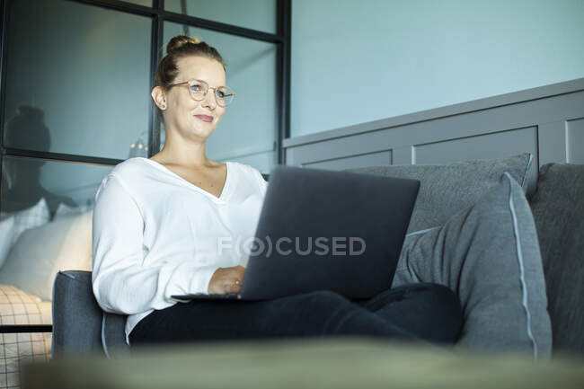 Woman working in hotel room, sitting on couch — Stock Photo