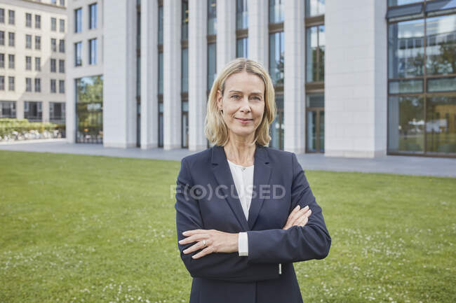 Portrait of confident businesswoman standing on lawn in the city — Stock Photo