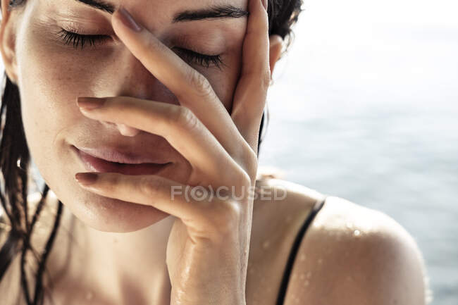 Donna con gli occhi chiusi e la mano sul viso dopo il bagno, primo piano — Foto stock