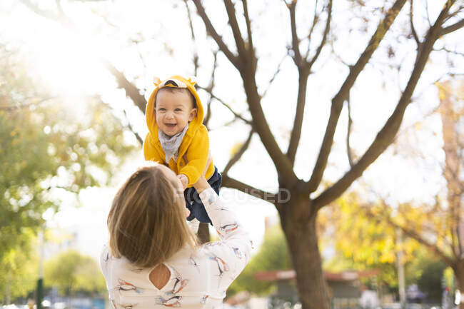 Мати піднімає щасливого хлопчика в парку — стокове фото