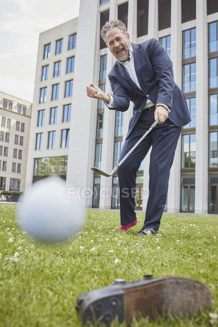 Felice uomo d'affari maturo giocare a golf sul prato in città — Foto stock