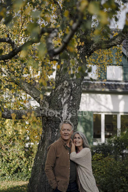 Старшая пара в саду своего дома осенью — стоковое фото