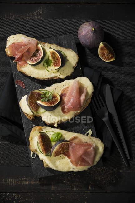 High angle view of baked cheese bread with fig slices and ham served on table — Stock Photo