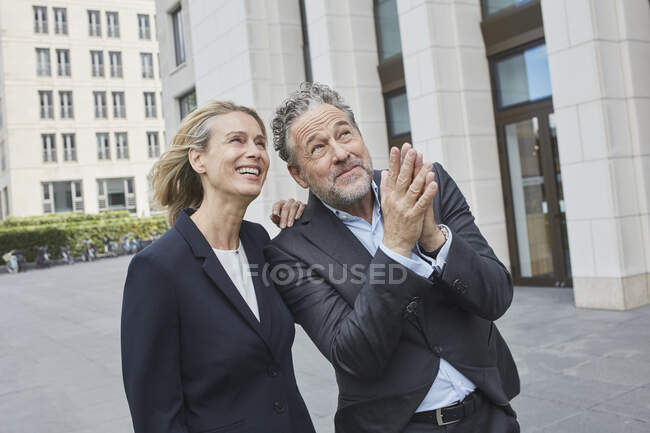 Happy businessman and businesswoman in the city looking up — Stock Photo