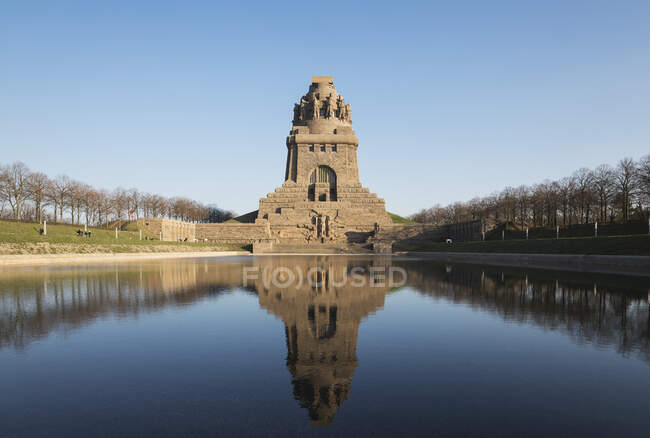 Lago di lacrime con riflesso di Vlkerschlachtdenkmal contro cielo azzurro chiaro, Sassonia, Germania — Foto stock