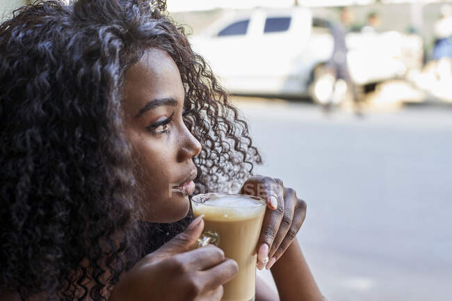 Portrait of young African woman in a cafe looking out of the window — Stock Photo