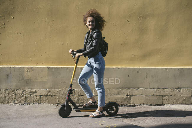 Ragazza sorridente adolescente con scooter in città — Foto stock