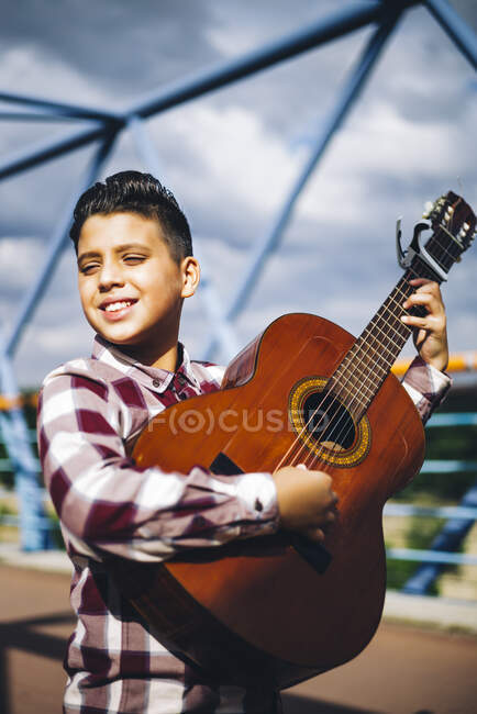 Gypsy boy playing guitar on a bridge — Stock Photo