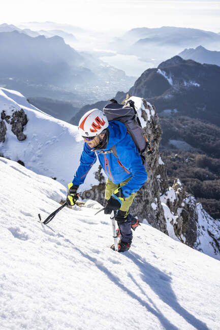 Alpinista ascendiendo una montaña nevada, Orobie Alps, Lecco, Italia - foto de stock