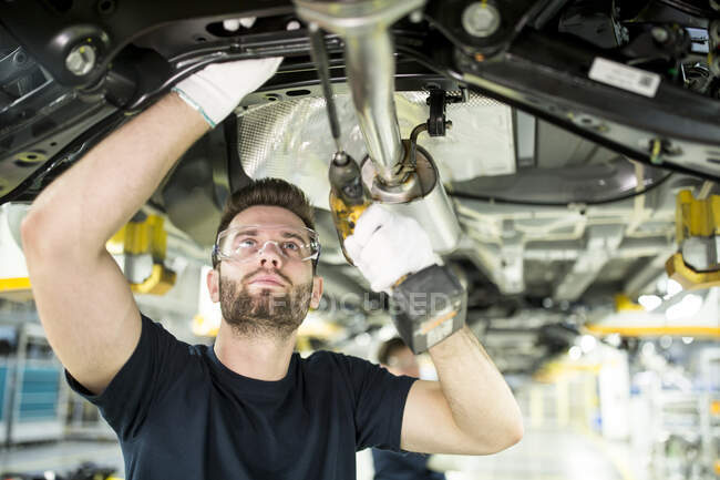 Homem trabalhando no carro underbody na fábrica moderna — Fotografia de Stock