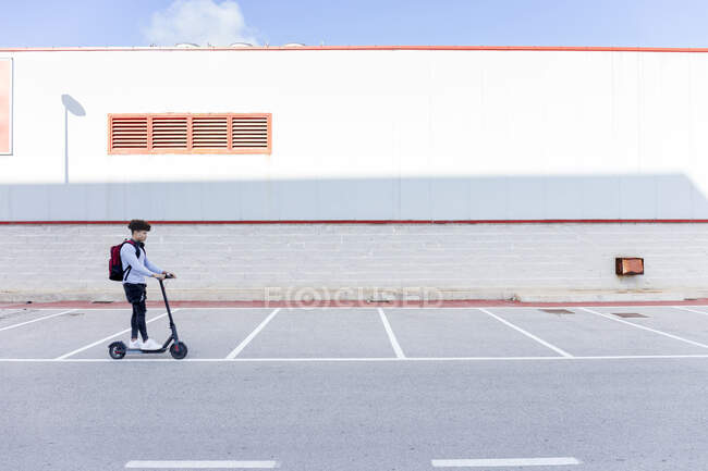Jovem montando e-scooter no deck de estacionamento — Fotografia de Stock