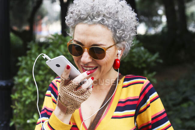 Retrato de mujer madura perforada usando teléfono inteligente al aire libre - foto de stock