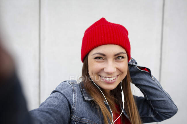 Donna che indossa pullover rosso e cappello squallido davanti a un muro — Foto stock