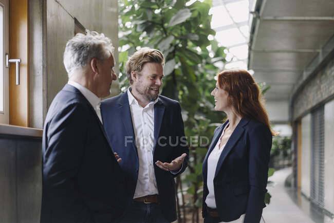 Gente de negocios sonriente hablando en un moderno edificio de oficinas - foto de stock