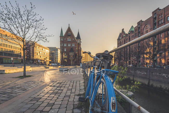 Bicicleta aparcada en el sendero contra Speicherstadt al atardecer en Hamburgo, Alemania - foto de stock