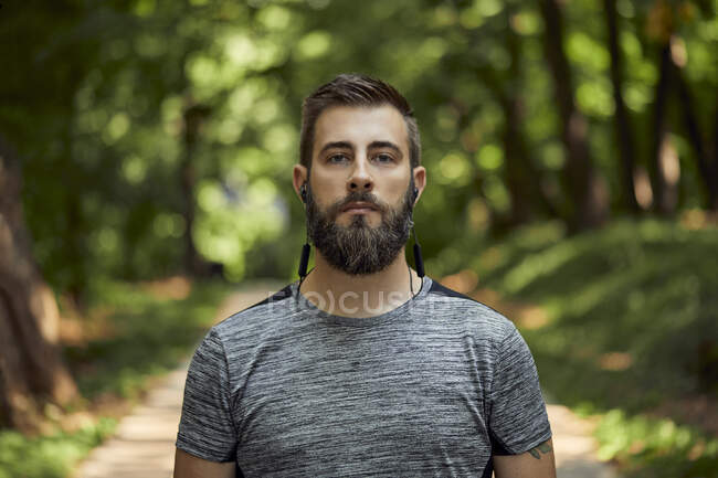 Porträt eines sportlichen Mannes mit Kopfhörern im Wald — Stockfoto