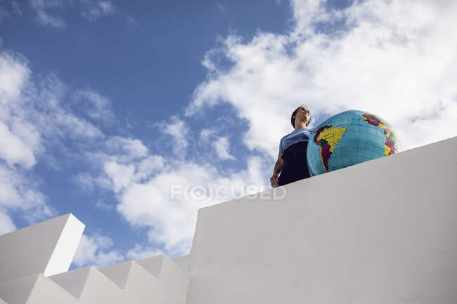 Donna d'affari sul muro bianco, guardando la distanza, tenendo il globo — Foto stock