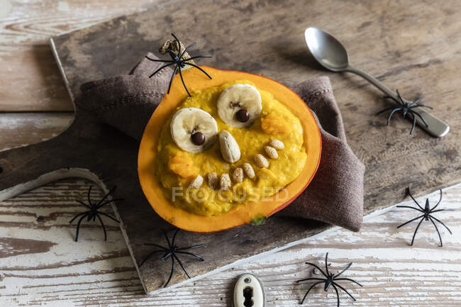 High angle view of pumpkin with anthropomorphic face and decorations on wooden table during Halloween — Stock Photo