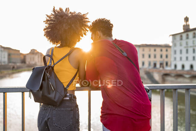 Jovem casal de turistas em pé em uma ponte acima do rio Arno ao pôr do sol, Florença, Itália — Fotografia de Stock