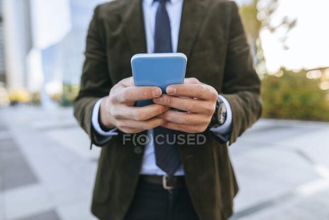 Крупный план бизнесмена, использующего смартфон на открытом воздухе — стоковое фото